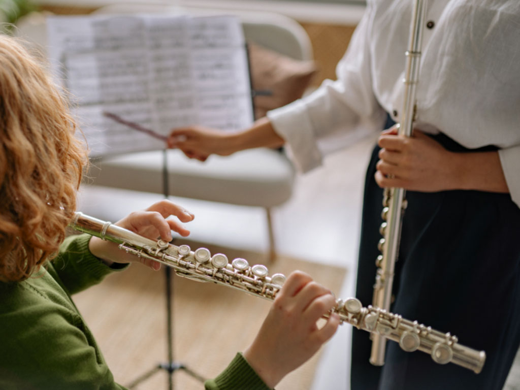 Child learning flute with teacher