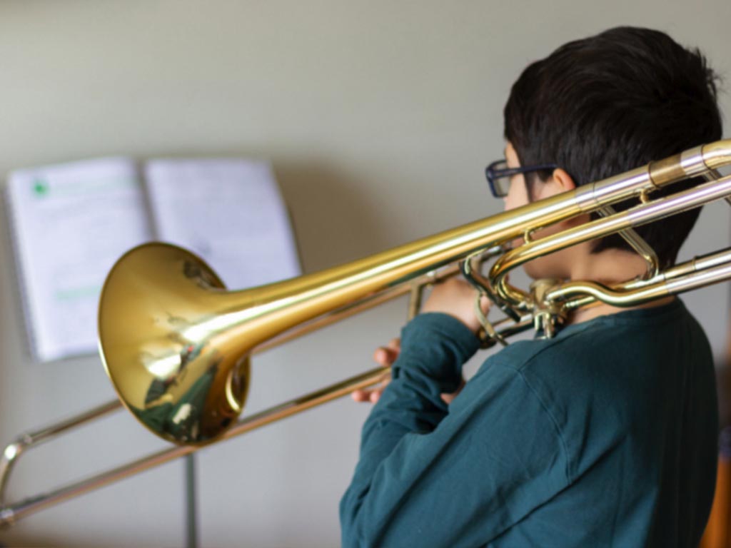 Child practicing trombone with teacher