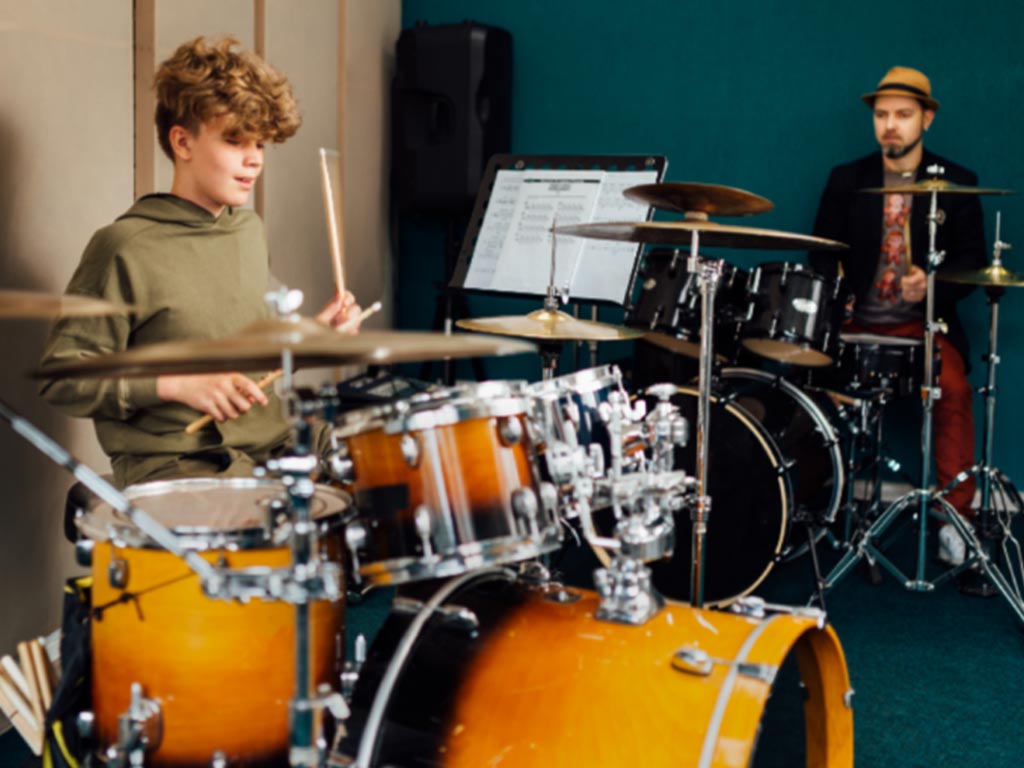 Student learning drums with teacher